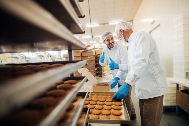 Workers packing cookies in boxes while standing in food factory.