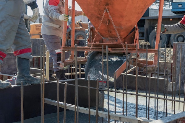 Workers pour concrete into the foundation at a construction site Concreting of the foundation during the construction of the building Concrete works