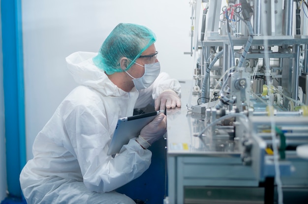 Foto lavoratori che producono maschera chirurgica in una fabbrica moderna, protezione covid-19 e concetto medico.