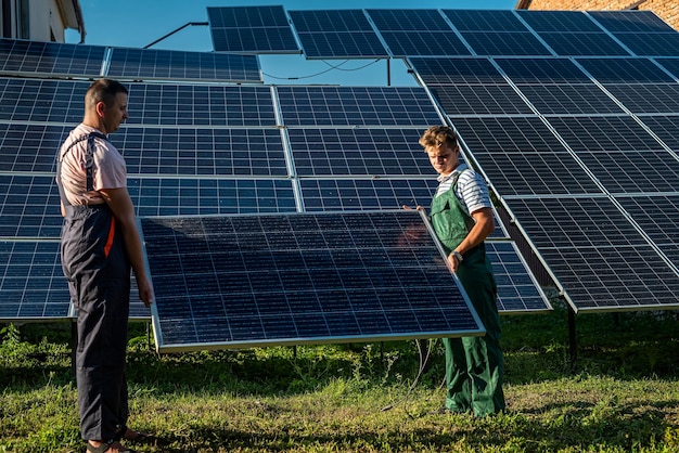 Workers in protective uniform carrying solar panel for installation at new station