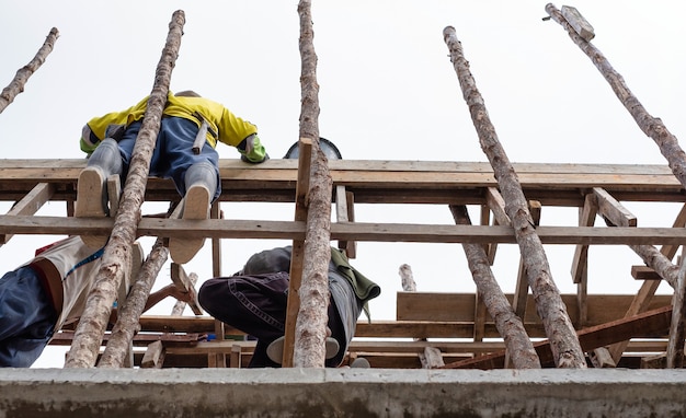 Workers standing on wood scaffolding in new house building