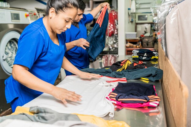 Workers in uniform folding clothes in a laundry service