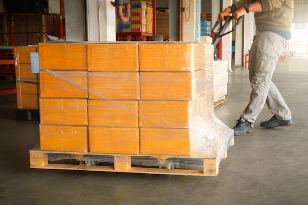 Foto lavoratori che scaricano scatole di pacchi su pallet nel magazzino distribuzione di rifornimenti spedizione del magazzino