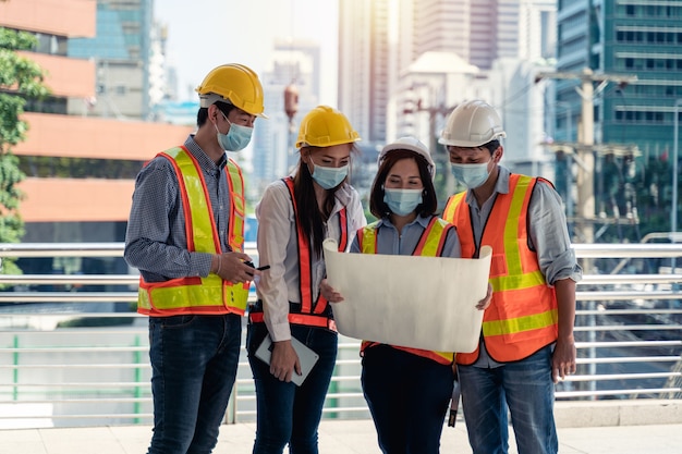 Workers waring surgical mask and safety white head to protect for pollution and virus in workplace during concern about covid pandemic