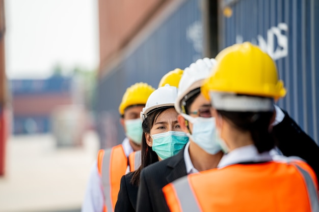 Lavoratori che indossano maschera protettiva e attrezzatura di sicurezza accanto ai container