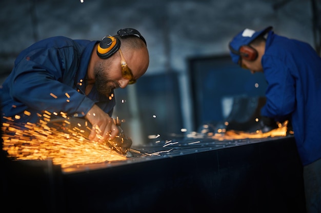 Lavoratori che lavorano con il metallo vicino a scintille arancioni