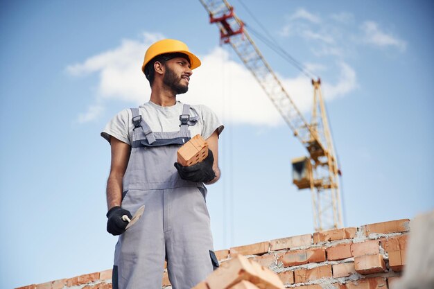 写真 青い空に逆らって働いているハンサムなインド人男性が建設現場にいます