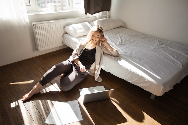 working beautiful young woman at home with laptop talking on the phone