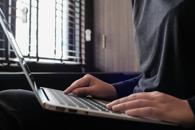 Working by using a laptop computer on wooden table Hands typing on a keyboard