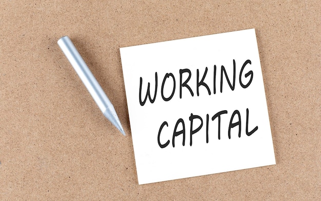 Working capital text on sticky note on a cork board with\
pencil