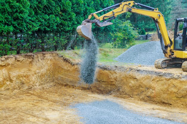 Working on a construction excavator moving gravel stones for foundation building