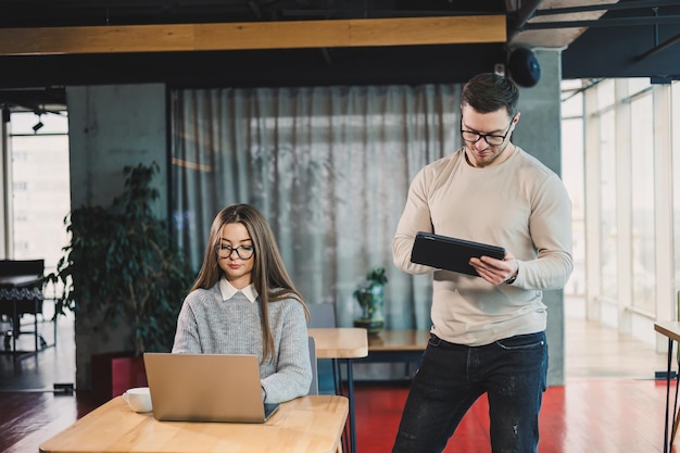 Working day in a modern office with workers in casual clothes male and female colleagues working with a laptop on a modern project