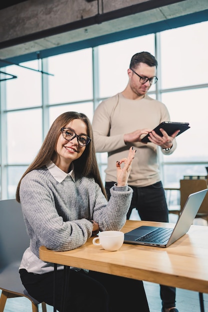 Working day in a modern office with workers in casual clothes male and female colleagues working with a laptop on a modern project