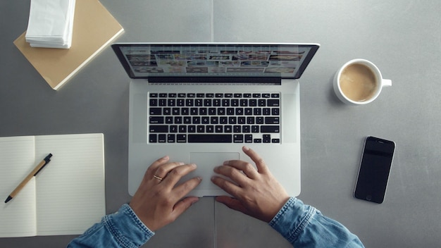 노트북 노트북과 남자의 손에 커피와 종이 메모가 있는 작업용 책상 상단 보기 위에서 작업하는 남자