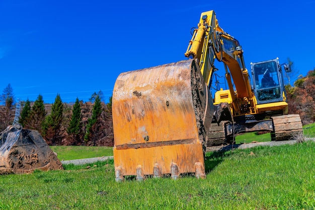 Working excavator on green plot of land preparation of digging pits natural background