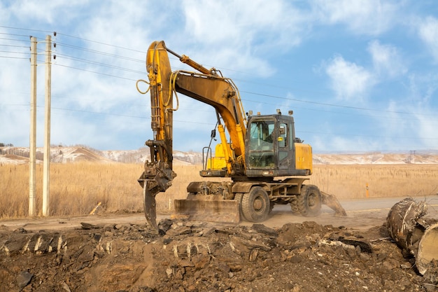 A working excavator with attachments on the construction of a road junction