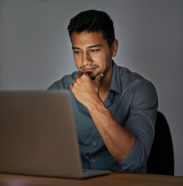 working from home as a boss shot of a confident young man working on a laptop in the office at night