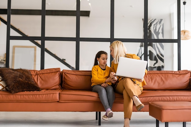 Working from home office with kid. Happy mother and daughter shopping online, using laptop together. Woman hugging child. Freelancer workplace. Female business, virtual communication.