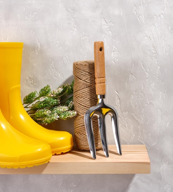 Working in greenhouse Skein of jute twine yellow rubber boots small rake on table Gardening tools