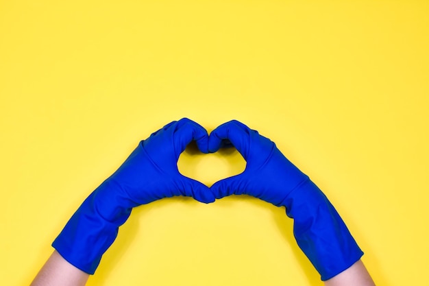ゴム製の保護手袋をはめた作業手は心臓を示しています 春先または定期的な清掃 清潔さの概念
