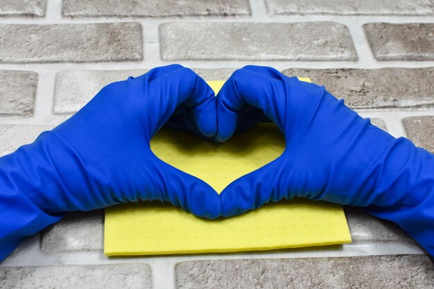 Working hands in rubber protective gloves show the heart Early spring or regular cleaning The concept of cleanliness