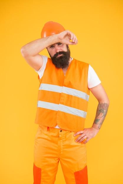 Working hard Tired construction worker mop sweat yellow background Construction engineer or builder in work uniform Building and construction industry Construction maintenance and repair work