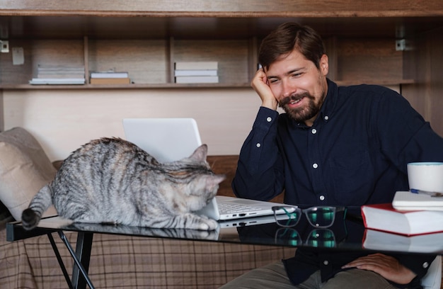 Working at home with pet laying on lap Man works from home typing on laptop