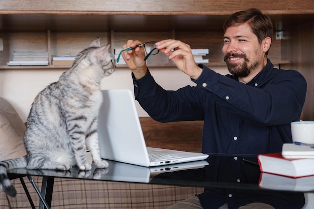 Foto lavorare a casa con animali domestici in grembo l'uomo lavora da casa digitando sul laptop