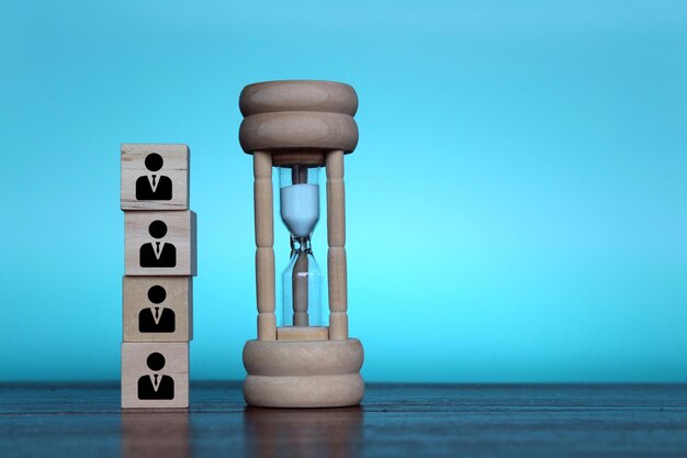 Working hours hourly wages deadline concept Hourglass and wooden cubes with employee icon