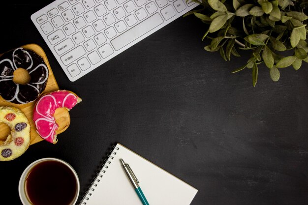 Working items with coffee and donuts on a black background