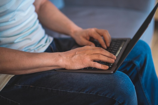 Working on laptop. Close up of mans hands holding lapotp