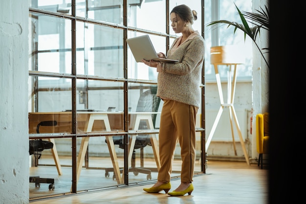 Working on laptop. Pregnant hard-working businesswoman wearing yellow shoes working on her laptop