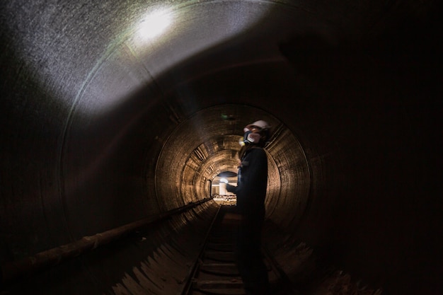 Saldatura di ispezione maschio funzionante sotterranea del tunnel dell'attrezzatura usando la torcia elettrica.