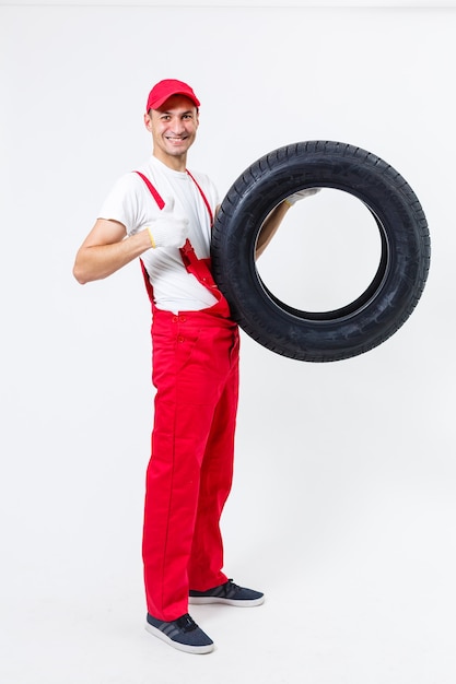 working man in full growth holds a tire on a white background