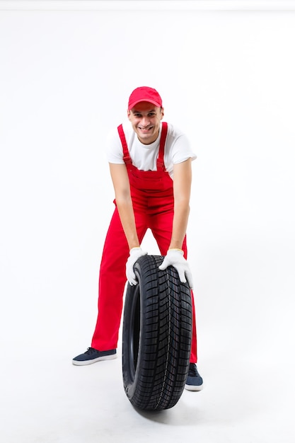 working man in full growth holds a tire on a white background