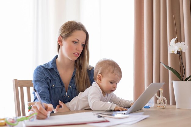 ラップトップとラップトップに子供を乗せたワーキングママ