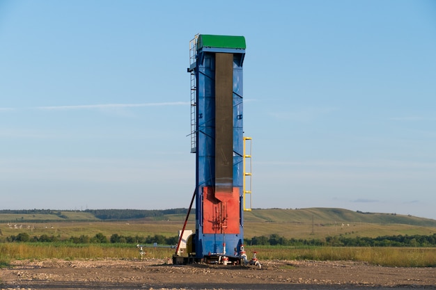 Foto pompa di olio funzionante a terra tra i campi verdi.