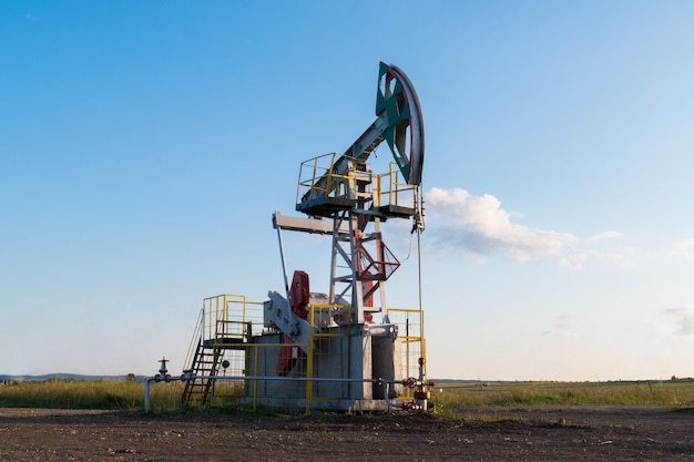 Working oil pump on the ground among the green fields