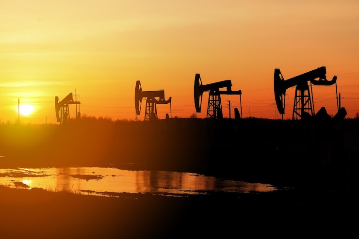 Photo working oil pump . silhouette of oil rocking chairs at sunset, a ray of sun. defocused, selective focus