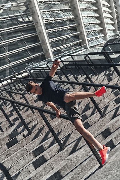 Working out on the stairs. Full length of young man in sports clothing jumping 