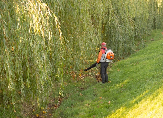 Working in the Park removes autumn leaves with a blower