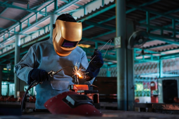 Lavoratore circa l'acciaio del saldatore usando la saldatrice elettrica