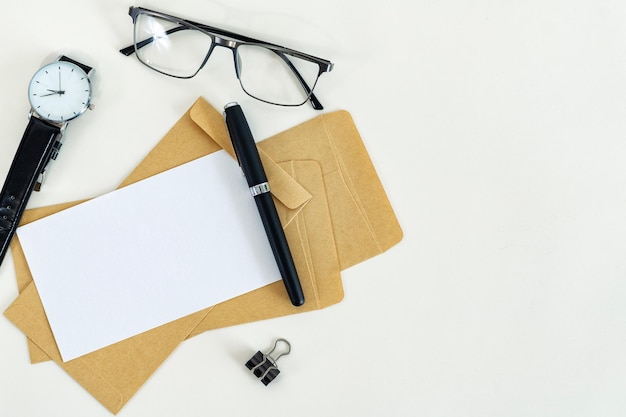 Working place Blank paper envelopes pen eyeglasses and watch on white desk