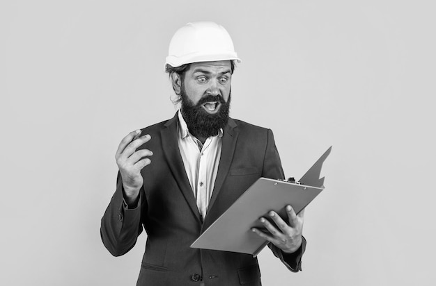 Working on project building concept builder or engineer in hard hat surprised mature architect in helmet making notes brutal bearded man work on construction site with documents