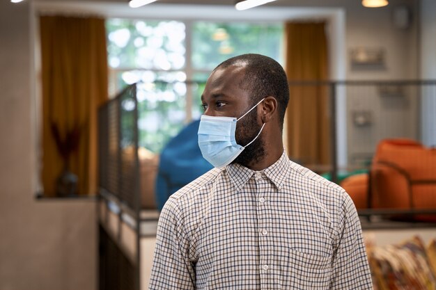 Working safely during coronavirus portrait of young afro american man male office worker wearing