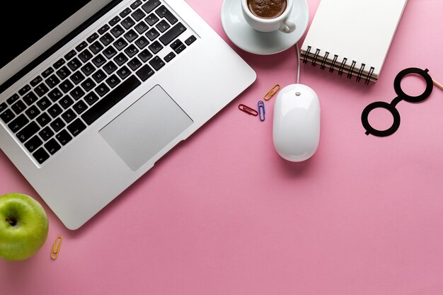 Funzionamento dello spazio di lavoro freelance concept vista superiore sopra il computer portatile piatto. sfondo rosa.