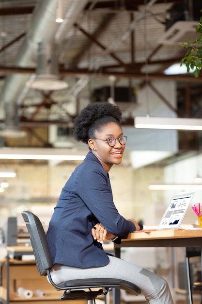 At working table. Curly dark-skinned interior designer sitting at the working table