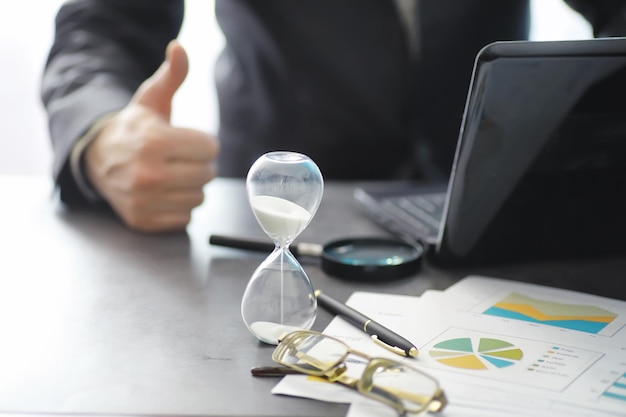 근무 시간은 시간 부족의 개념에 있는 보험 관리자와 은행가 사무실 직원의 모래시계 사무실 책상을 상징합니다.