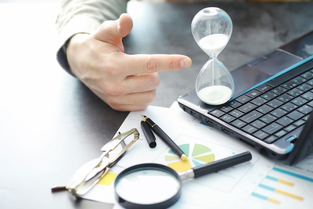 Photo working time symbolizes an hourglass. office desk with insurance manager and banker. office employee at the table. the concept of lack of time.