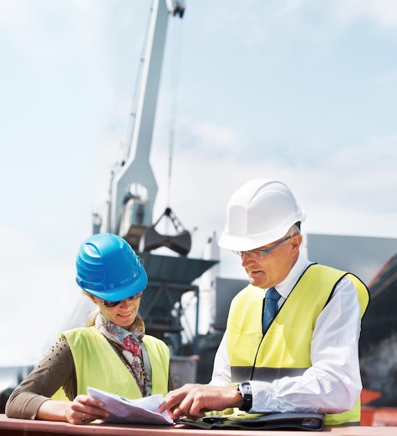 Lavorare insieme può rafforzare qualsiasi fondamento. due lavoratori portuali in possesso di scartoffie mentre sono in piedi nel cantiere navale.